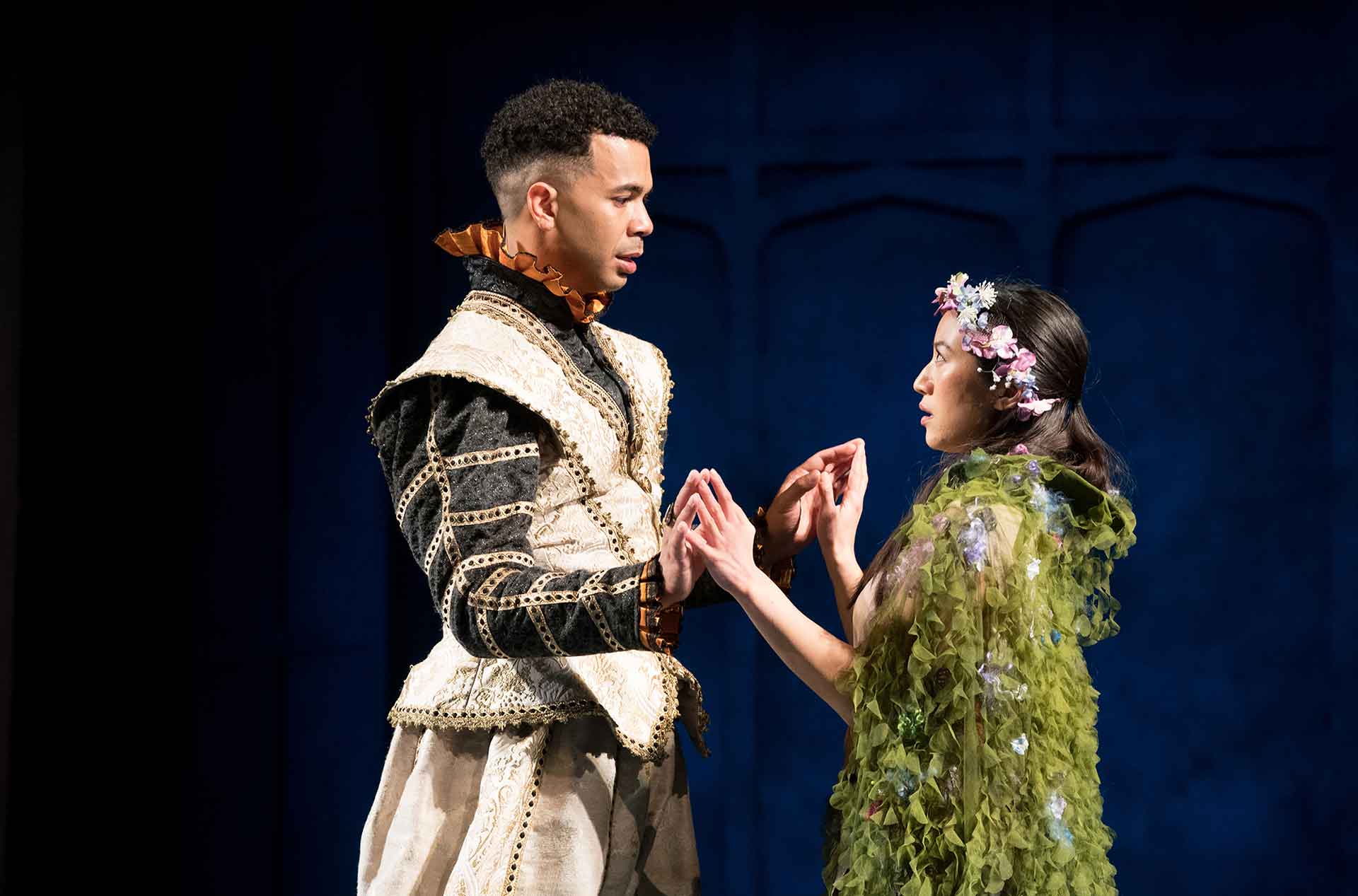 Young man and woman standing , facing each other, and holding hands.