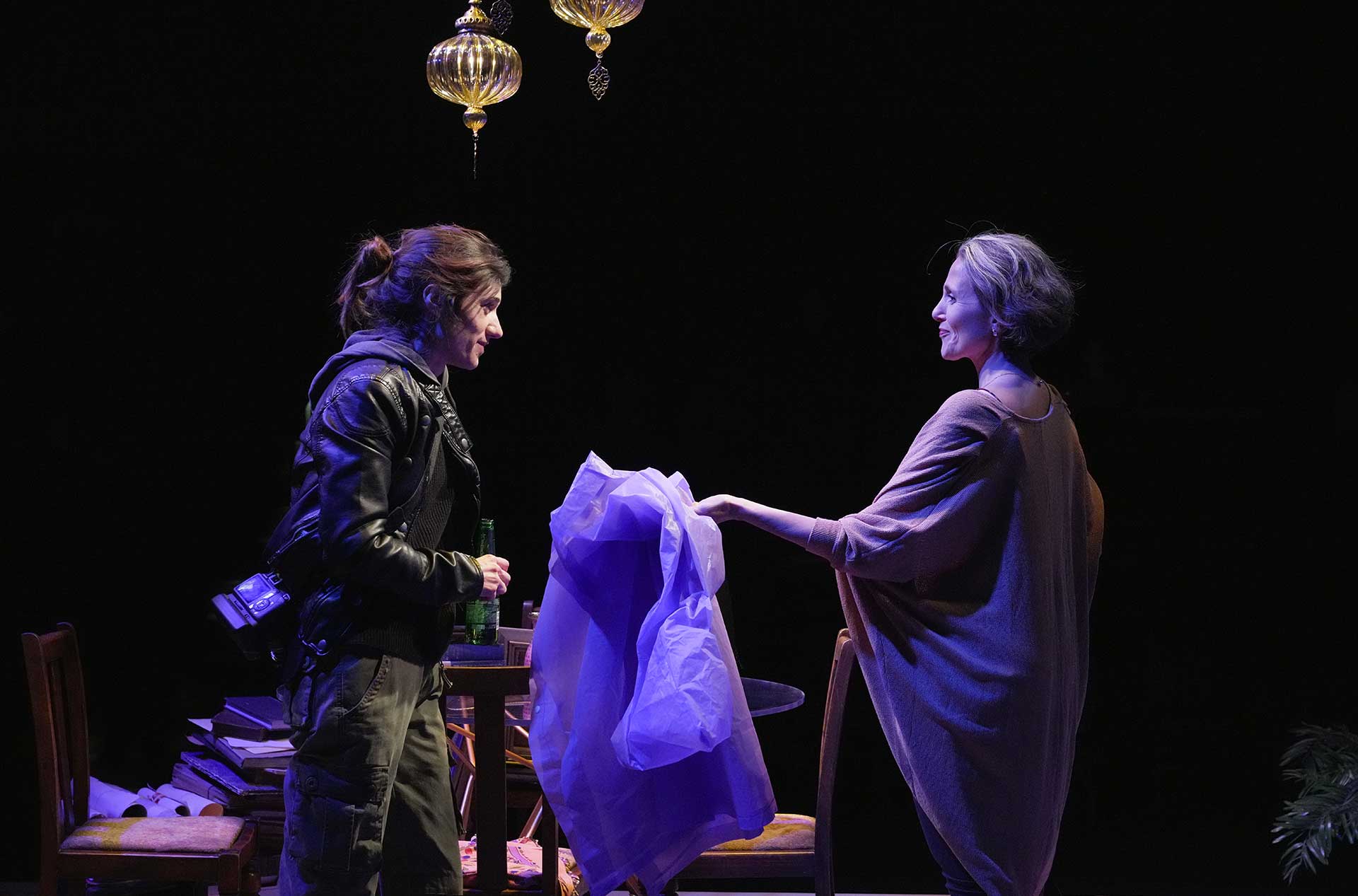 One person handing another an article of clothing.