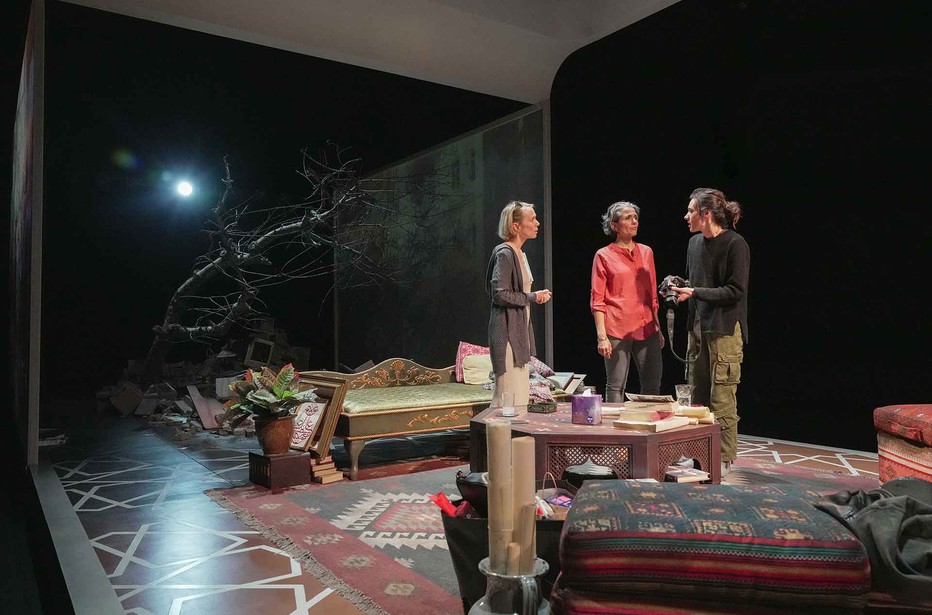 Three people talking in a group. One is holding a camera.