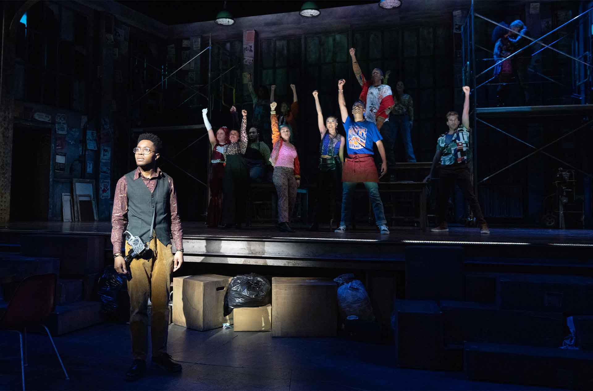 Person looking into distance with a group of people in the background holding their fist in the air.