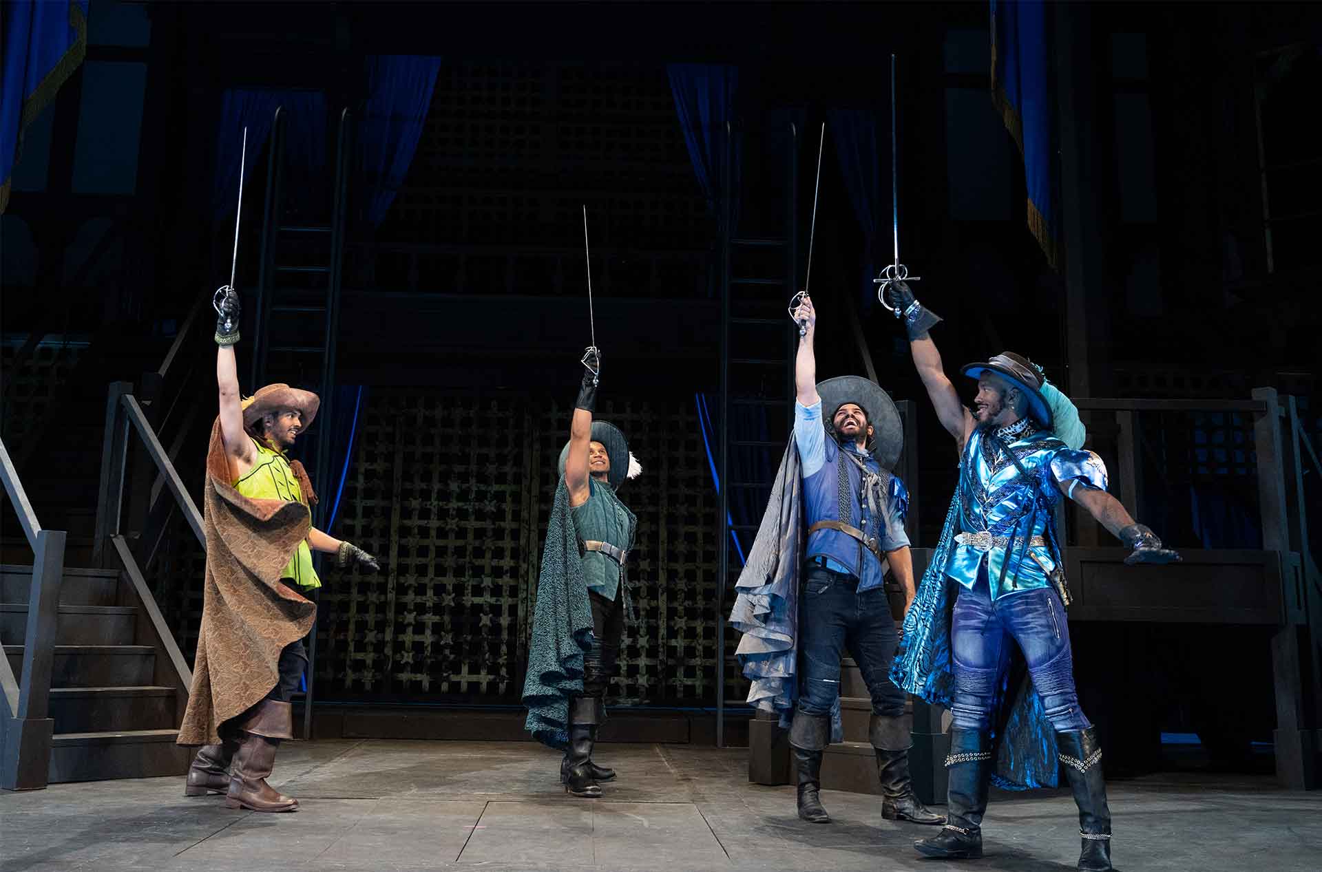 Four people standing with swords pointed to the sky.