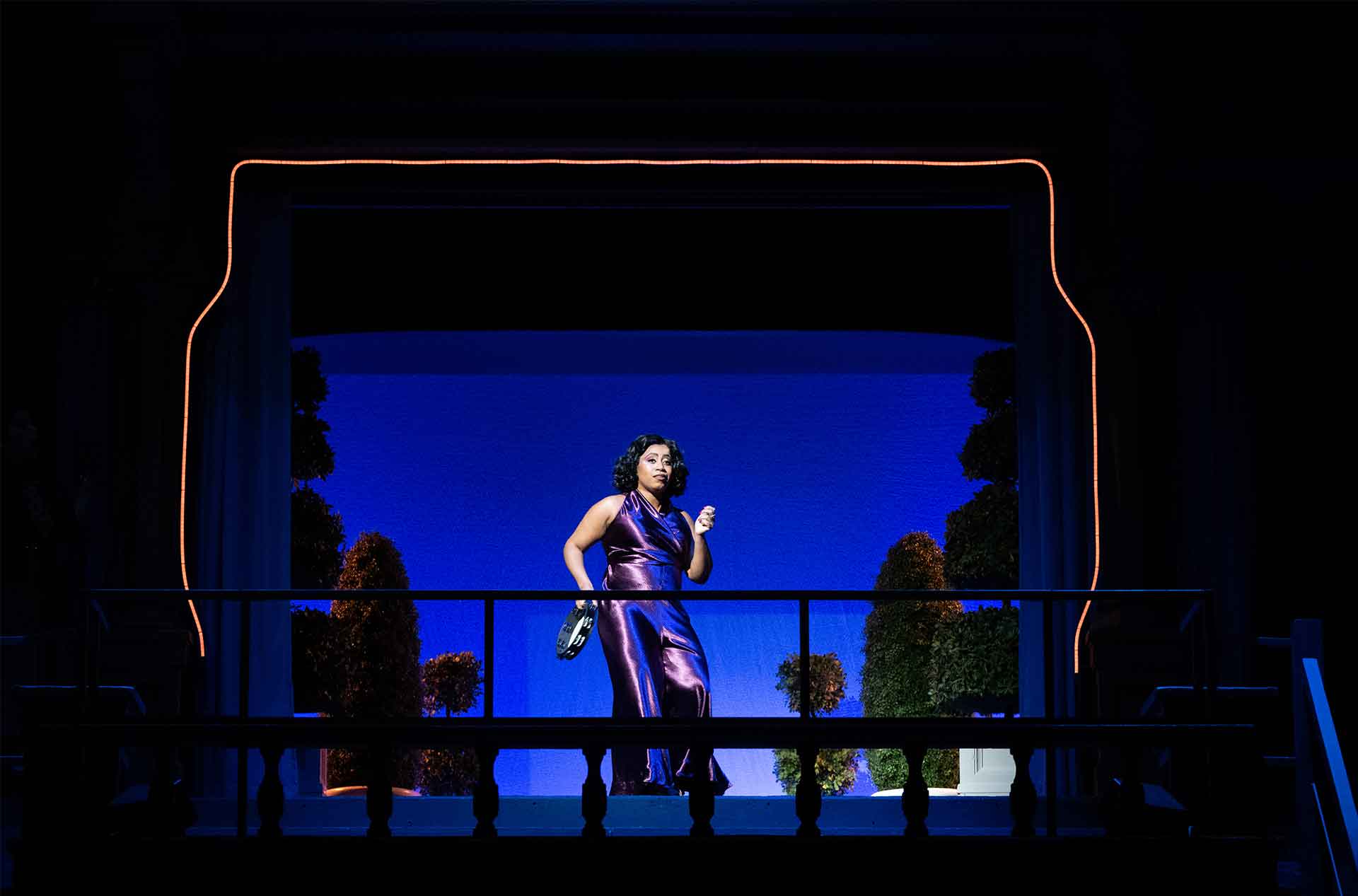 A person standing on a balcony playing a tambourine. 