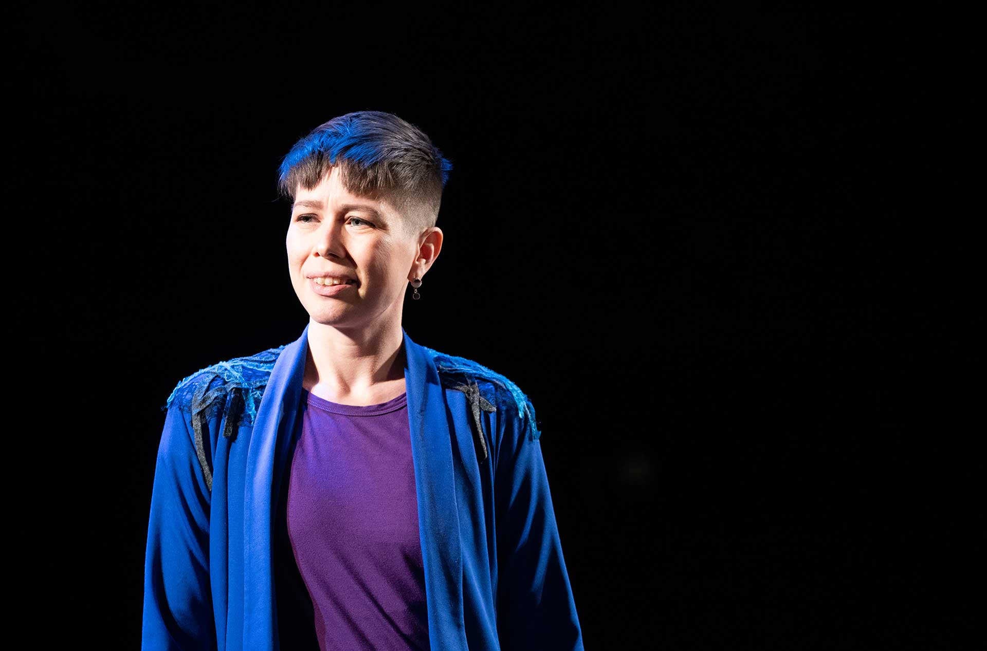 A person standing on the stage looking out toward the audience. 