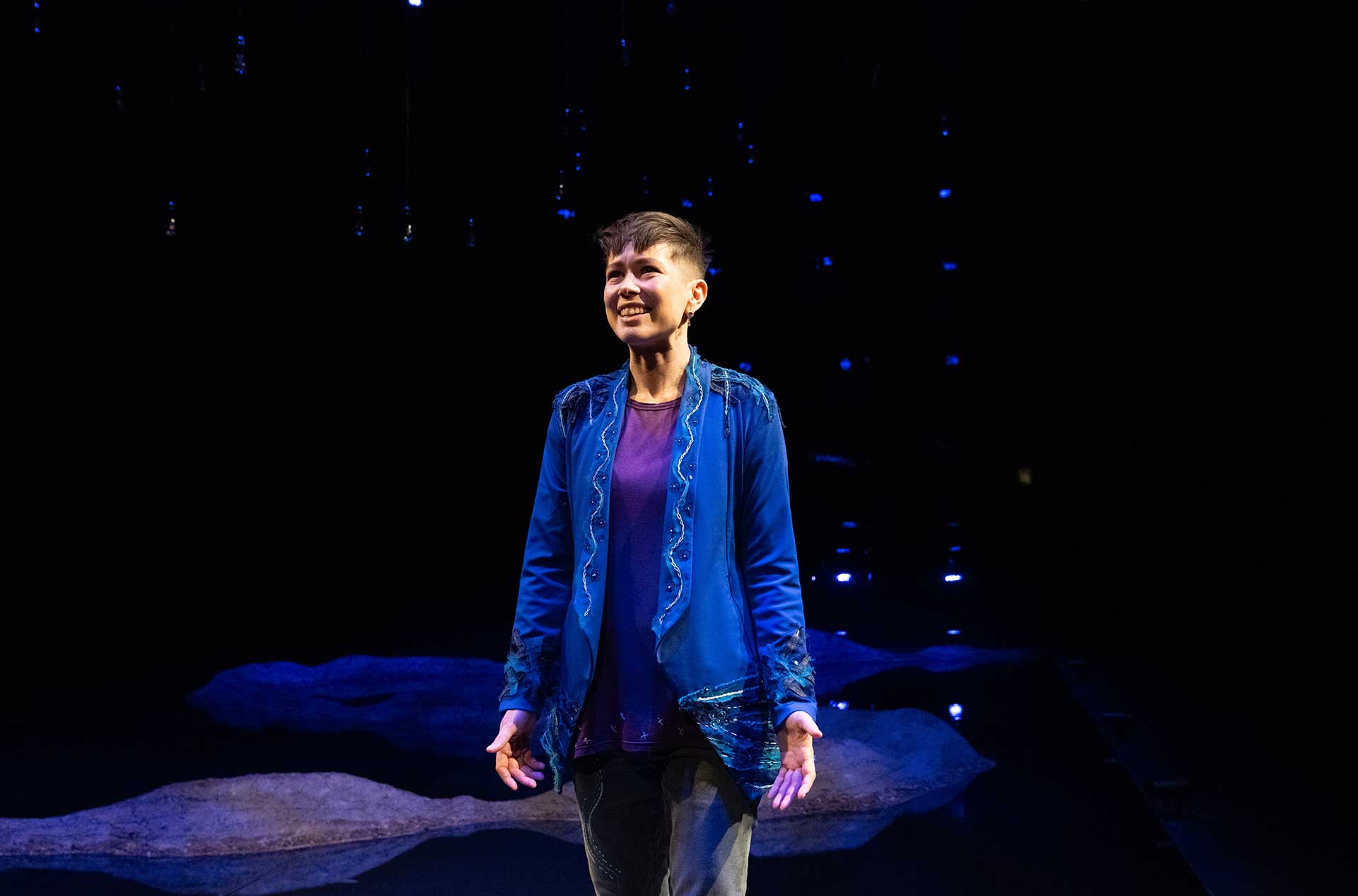 A person standing on the stage looking out toward the audience.