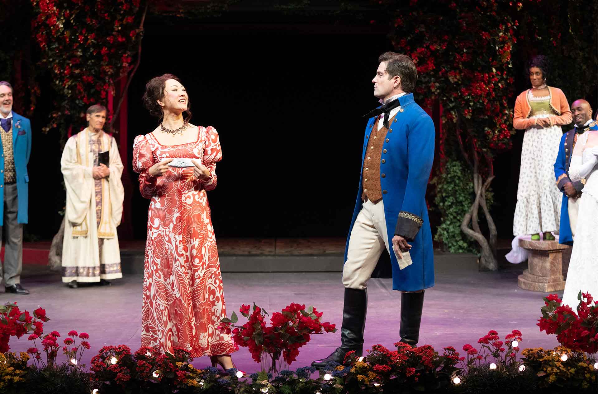 Two people in fancy clothing talking to each other while other are standing near by.