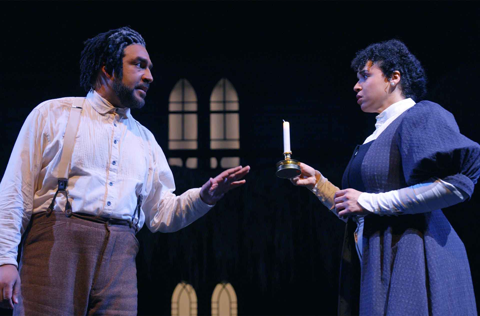 Two people talking while one holds a candle.