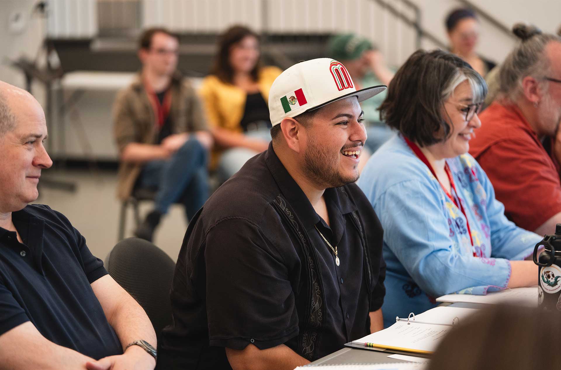 People seated side by side at a table laugh and engage with each other.