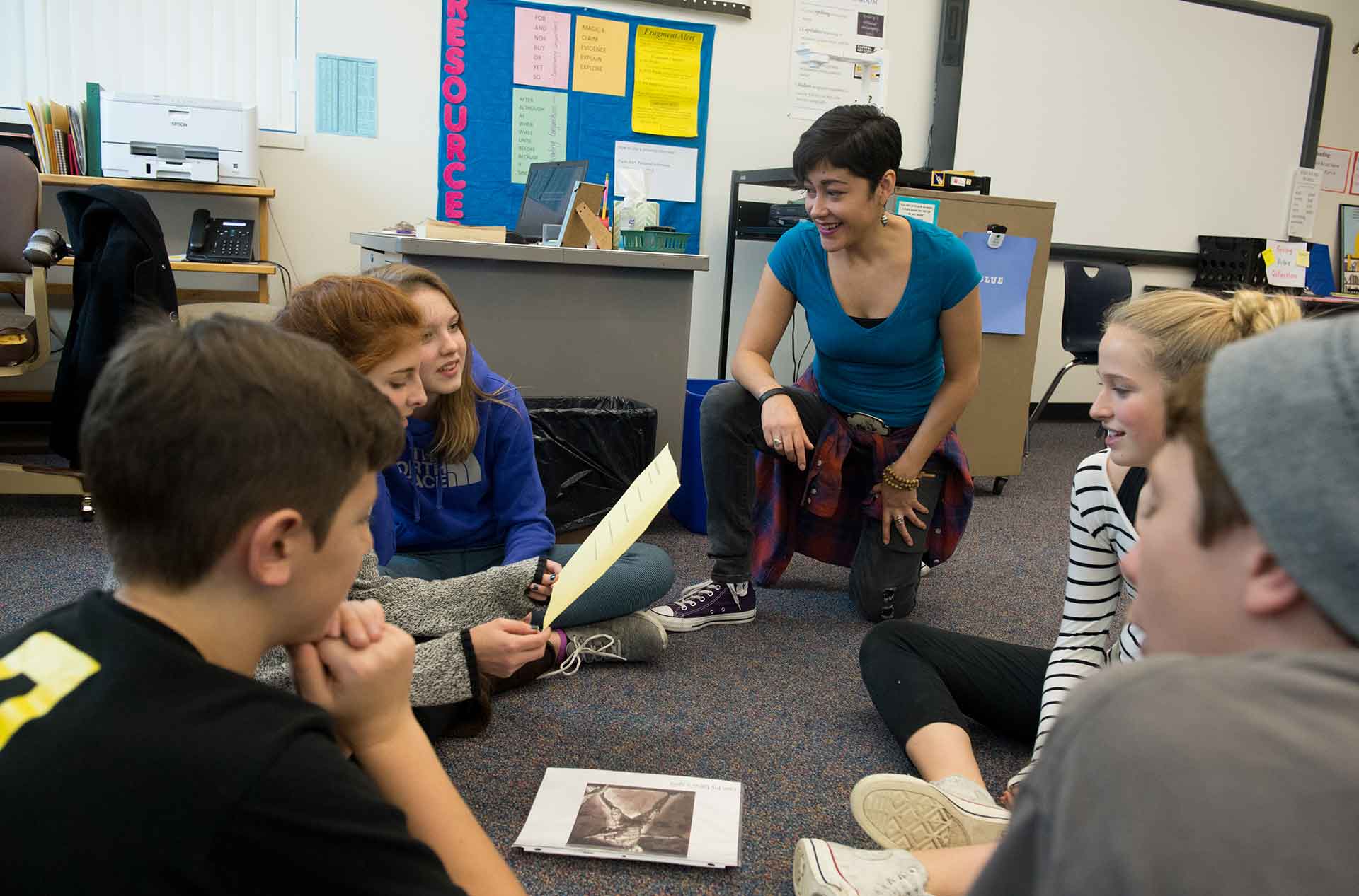 A small group of students listening a person kneeling beside them.