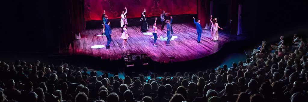 People dancing on the Angus Bowmer stage with the audience in the foreground.