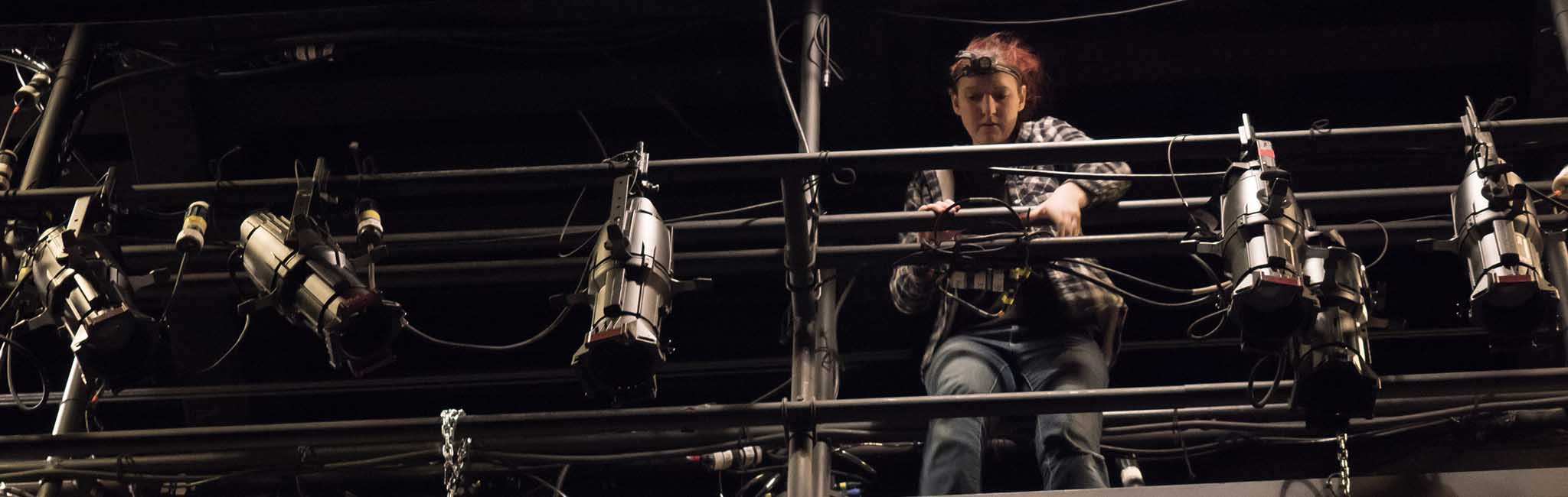 A person standing on scaffolding setting up lights.