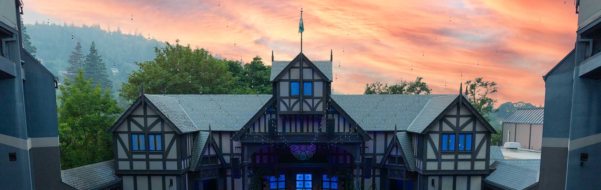 Tudor-style theater exterior at sunset with glowing sky.